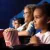 Kids watching a movie in a theater with popcorn