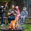 A father with 3 kids around a campfire