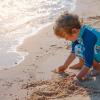 Young boy on the beach playing in sand