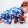 Young child with red hair sleeping and holding a stuffed animal