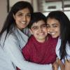 Boy hugged by sister and mother, all smiling