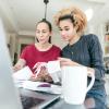 Two women sitting at a computer looking at recipes working on a budget 