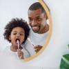 African American father and son looking in a mirror and brushing their teeth