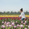 A young girl in a white top and jean shorts walks through a field of tulips during the annual Skagit Valley Tulip Festival