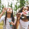 Two girls blowing bubbles outside 