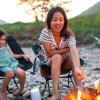 A mom and daughter play campfire games around the campfire while roasting marshmallows and making s'mores