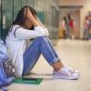 a frustrated student sits with head in hands in front of her locker, signs of toxic achievement culture