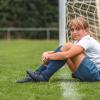 Girl sitting on the grass next to a soccer ball