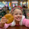 Young girl smiling and holding a bagel at one of seattle's best bagels shops