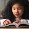 A young girl reads a book about science for kids