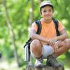 Boy sitting on a rock in the forest at a one-day or drop in Summer camp 