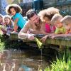 A group of kids on a small bridge over a pound at a seattle outdoor summer camp