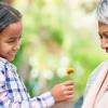 Young girl giving older woman a flower and spreading kindness