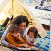 Mom reading with two kids on the floor of their bedroom Passover books