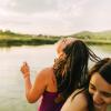 two teens laugh by a lake at dusk