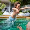 Boy jumping in his father in a swimming pool and demonstrating water safety for families 