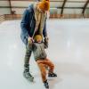 Boy and his dad learning to ice skate at an outdoor holiday ice-skating rink near Seattle