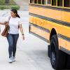mom and son walking home after school next to a yellow school bus