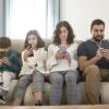 family sitting on a couch looking at their cell phones