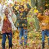 Two girls and a boy play in colorful leaves enjoying the season.