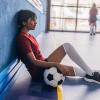 girl sitting down in a gym with soccer ball