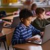 Kids sitting in a classroom all looking at laptops