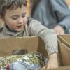 young boy putting food in a box at a food bank
