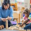 A teacher with kids in a day care playing with blocks 