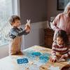 A family crafts snowflakes together in front of a window as a winter activity