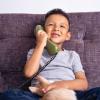 happy little boy talking on vintage green landline phone at home