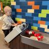 young child playing at the water play area at KidsQuest, offering discounted weekend admission for families Super Bowl weekend