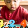 Little boy playing with mathematics wooden toy at child care