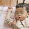 Little boy toddler adorably sleeping in his baby cot