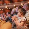 little girl clapping hands in a concert hall