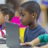 boy using a computer and ear buds in a classroom