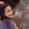 A young girl creates chalk art on the sidewalk.