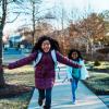 two girls running down the street happy to be out of school
