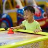 little boy playing air hockey at an arcade