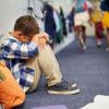 little boy sitting in corridor anxious at end of school 