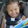 girl in a car seat with a fun car toy happy on a road trip