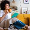 woman sitting on a couch with a cup of coffee and a book