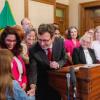Gov. Bob Ferguson handing over his pen to a child