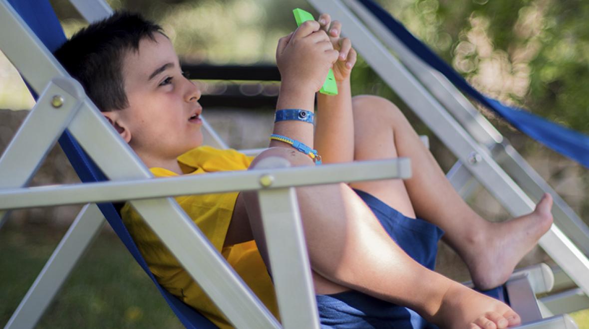 Boy outside with phone in lawn chair