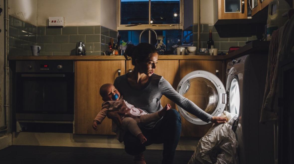 Mom holding baby and washing clothes