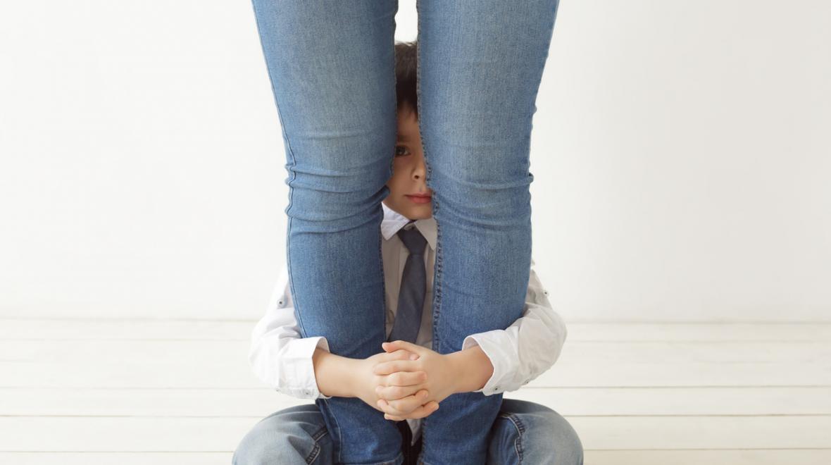 Introverted child hides behind his mother's legs