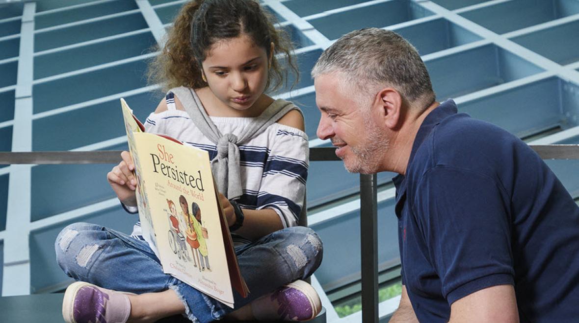 Young girl reading a book to her father at the Seattle Public Library Central Branch