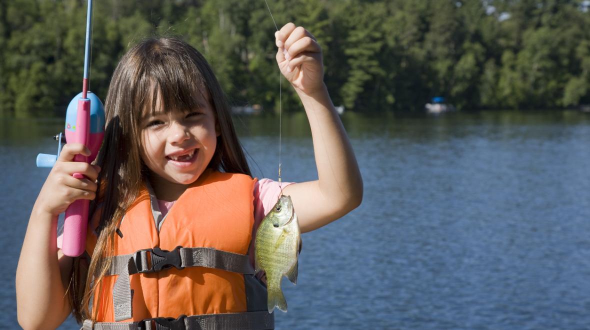 girl holding up fish fishing wearing life jacket where to go fishing with kids near seattle