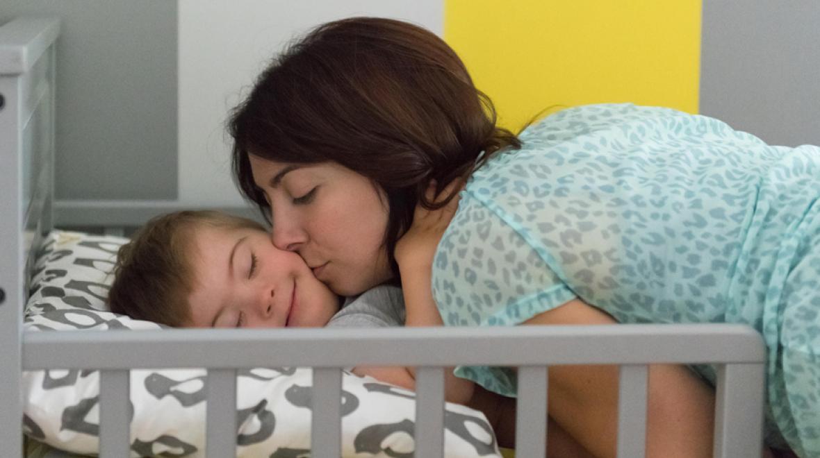 mother kissing her child with down syndrome at naptime