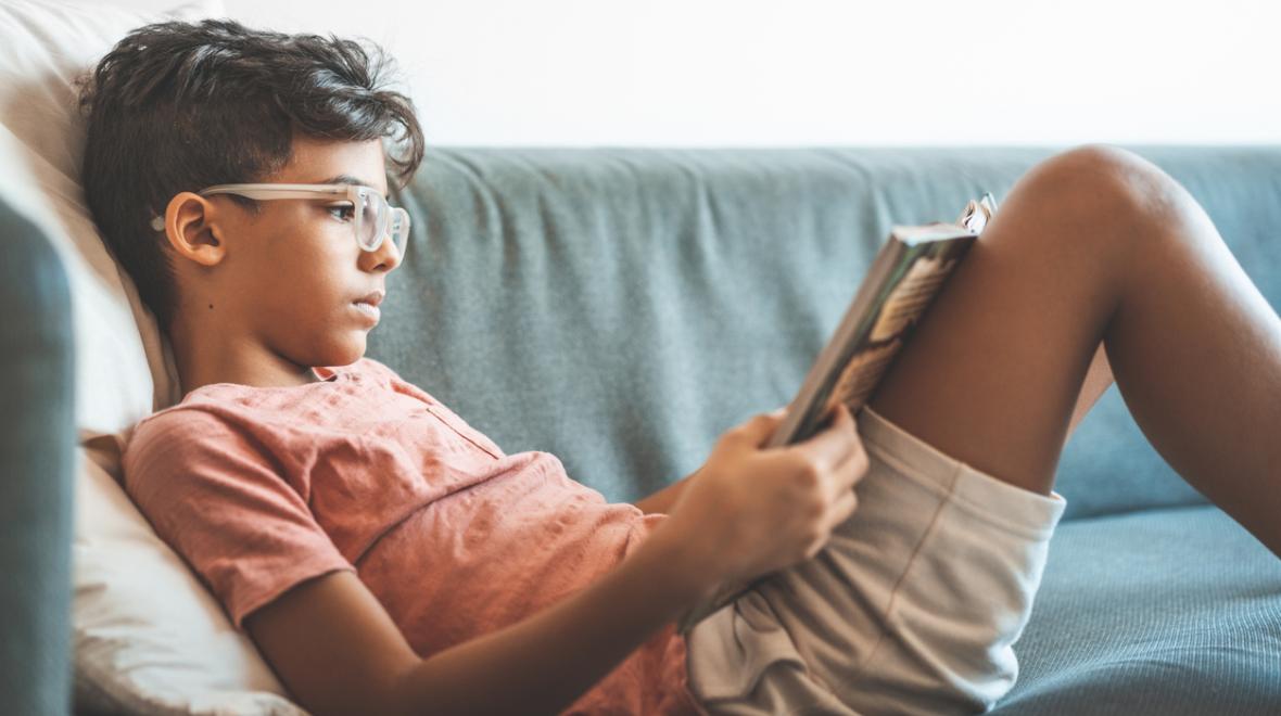 tween boy reading a book on the couch seattle area library summer reading programs for kids and families