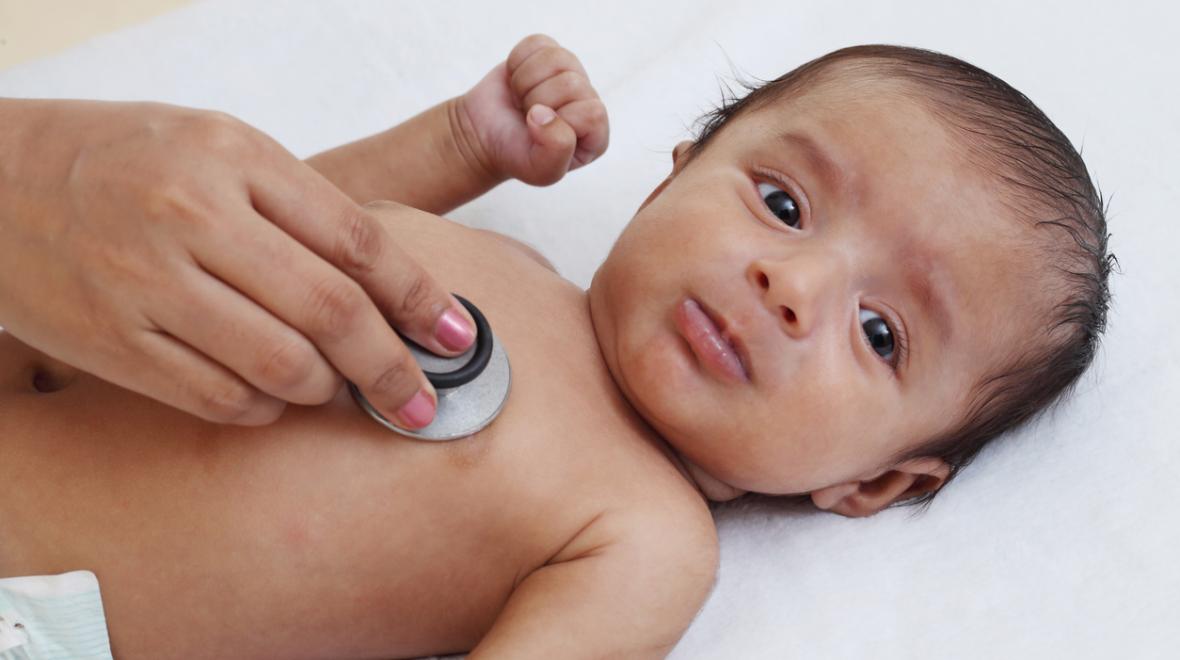 hand holding a stethoscope to a baby's bare chest
